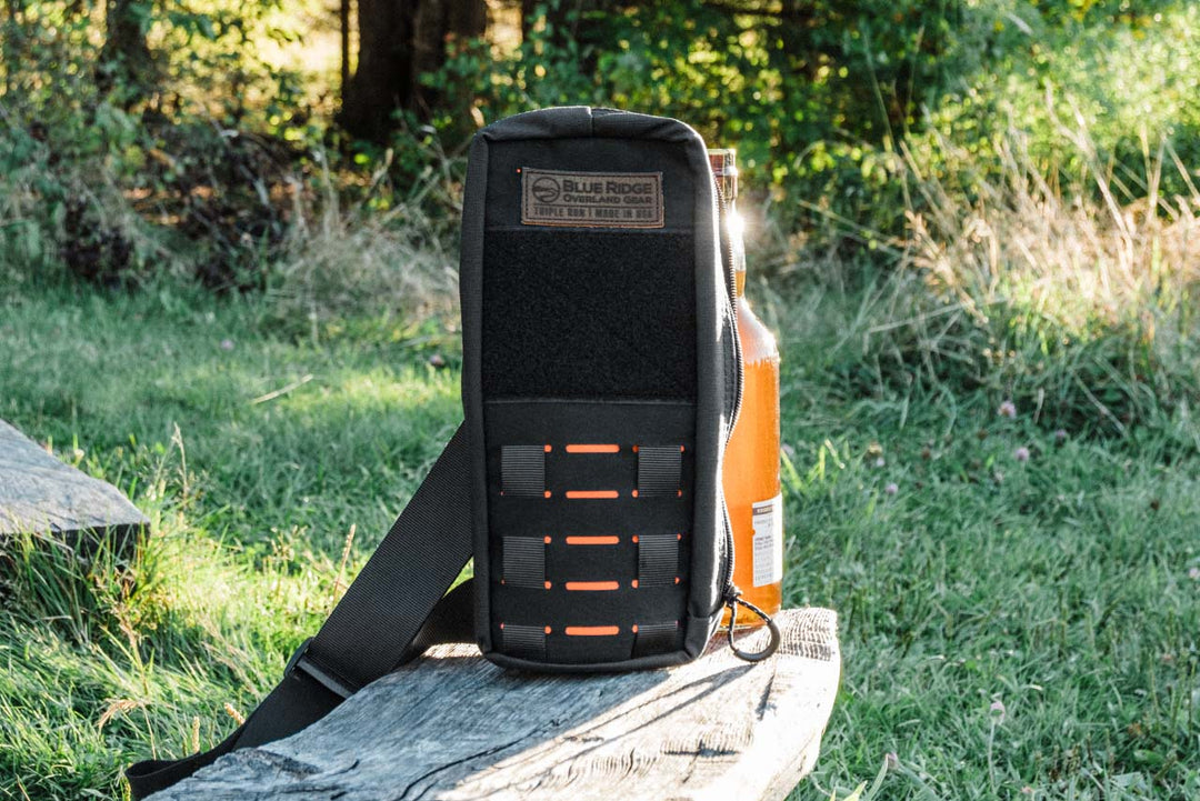 Bootlegger bourbon, whiskey bag - lifestyle image outdoors in natural setting on wood bench with bottle