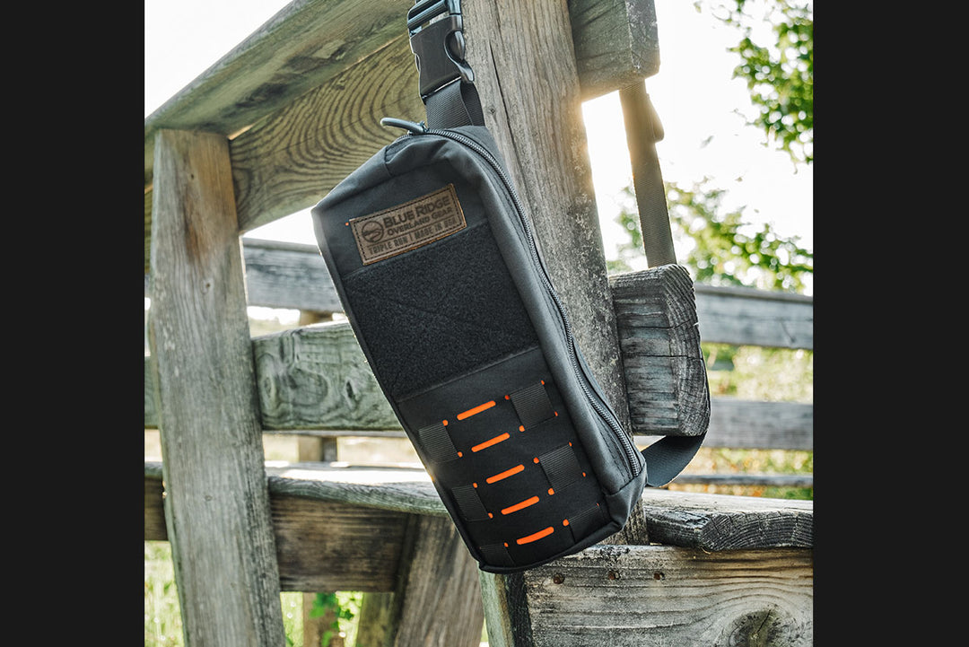 Bootlegger bourbon, whiskey bag - lifestyle image outdoors in natural setting hanging from wooden bench.