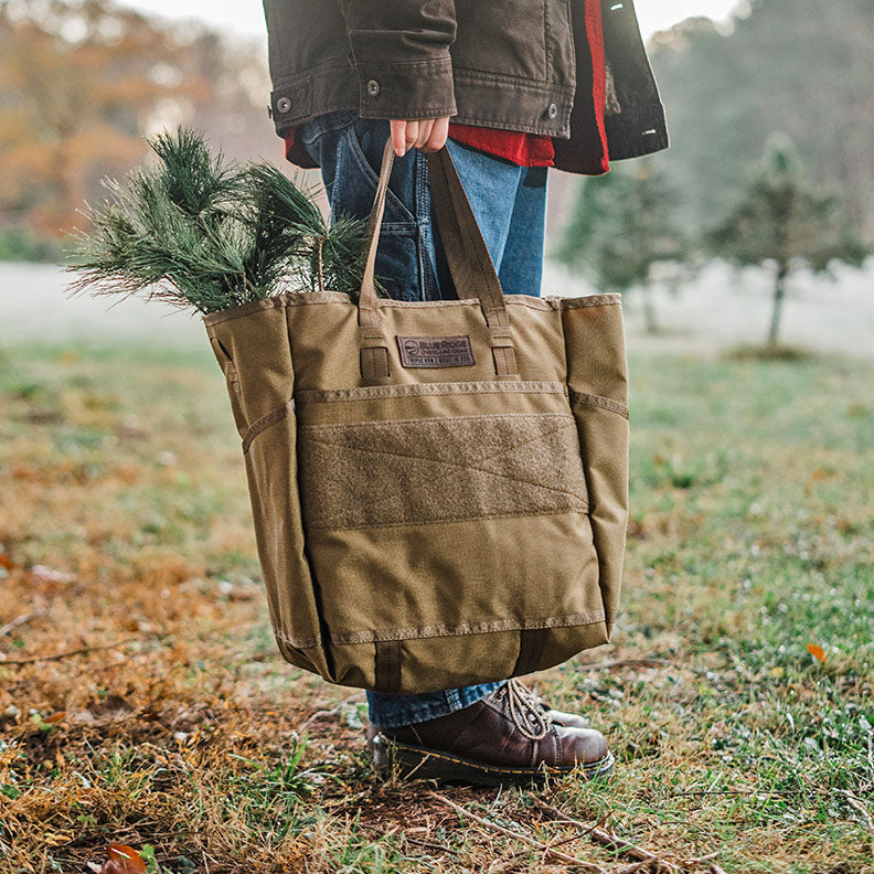 Person carries Christmas greenery in Tactical Tote Bag (made in the USA by Blue Ridge Overland Gear) in outdoor scene.